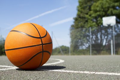 A-basketball-on-asphalt-with-a-hoop-in-the-background